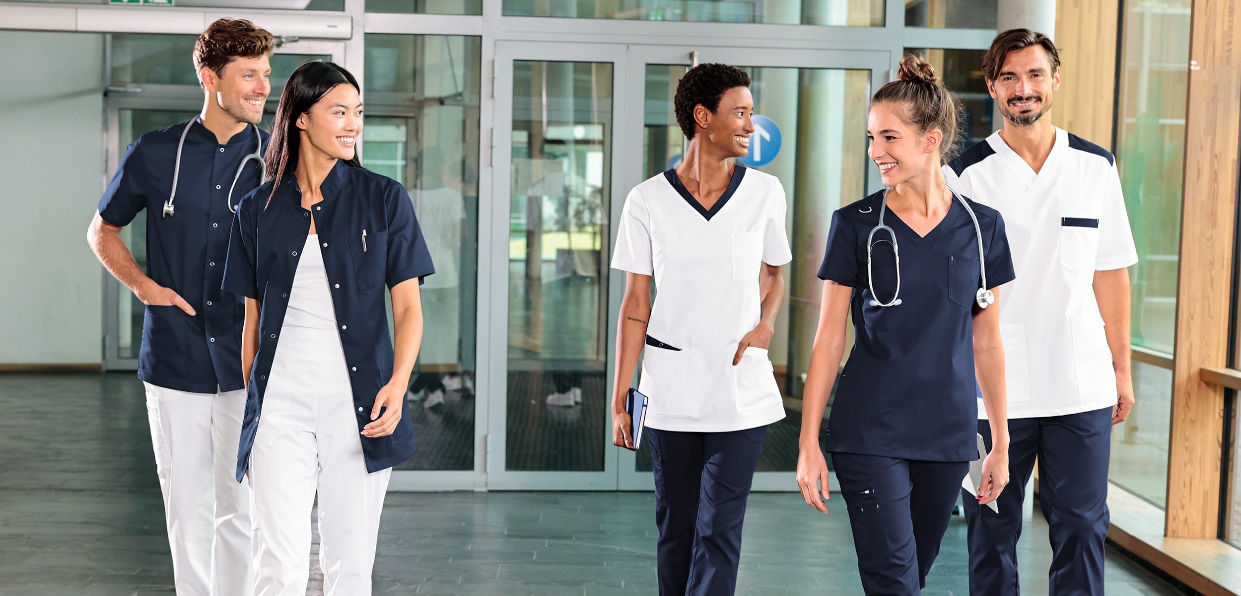 Teamaufnahme im Krankenhaus, 3 Damen- und 2 Herren-Models in weiss & dunkelblauer Ausstattung von CLINIC STRETCH.
