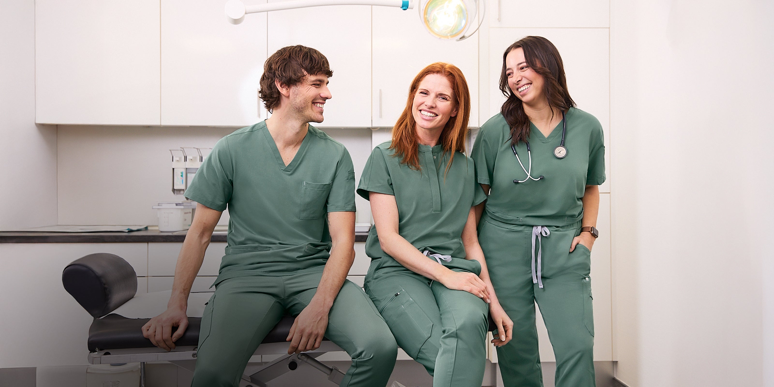KAERE Teamausstattung in Grün, 2 Damen- und 1 Herren-Modell in einer Arztpraxis.